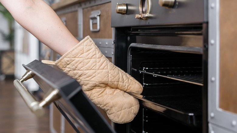 Reaching into the oven using mitts
