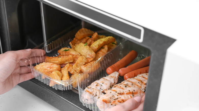 person putting meat into microwave