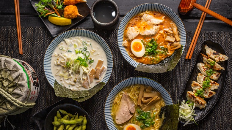 Three bowls of ramen, edamame, and potstickers