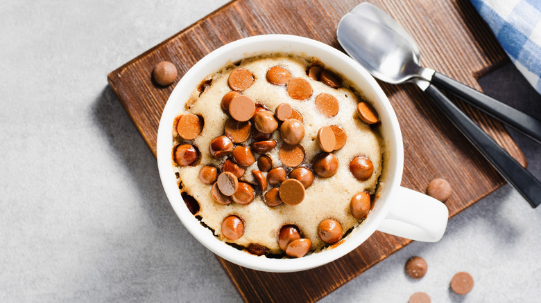 Overhead shot of a peanut butter chip mug cake with two spoons