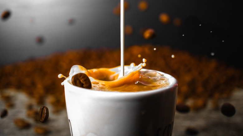Creamer being poured into a cup of coffee