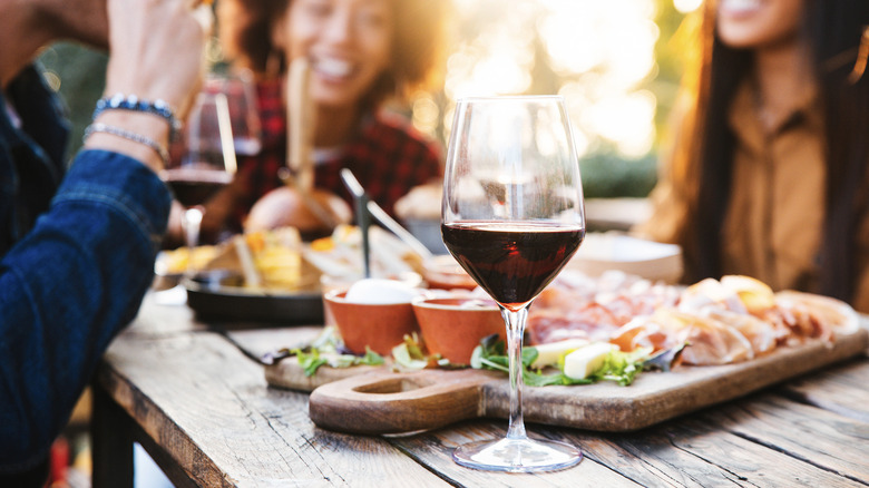friends enjoying glass of red wine and charcuterie outside