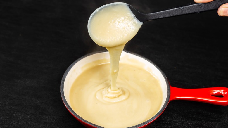 Cheese fondue poured by a spoon
