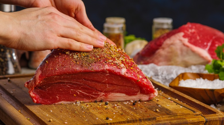 person rubbing spices into meat