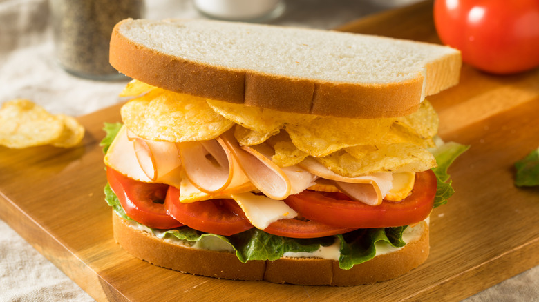 Potato chips on turkey, tomato, and lettuce sandwich