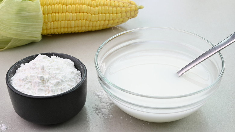 Bowl of cornstarch slurry alongside small bowl of cornstarch and whole ear of corn