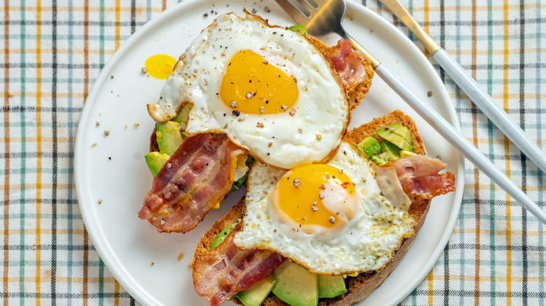 Fried eggs on avocado and bacon toast