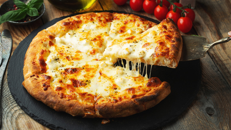 Close up of a melty cheesy pizza on a wooden table.