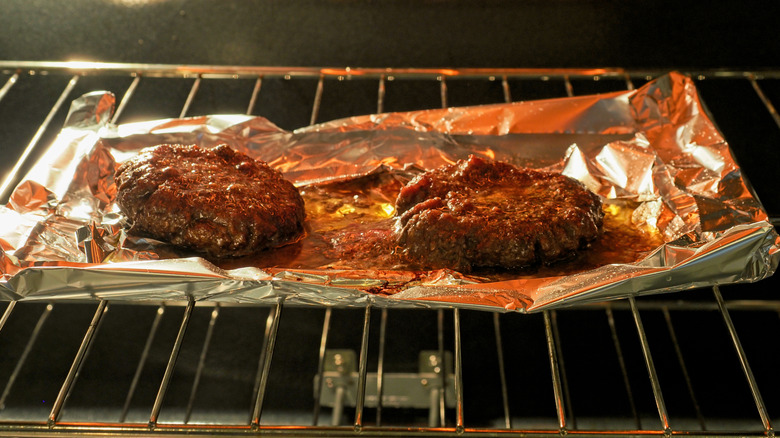 Burgers on a piece of foil, being cooked in an oven