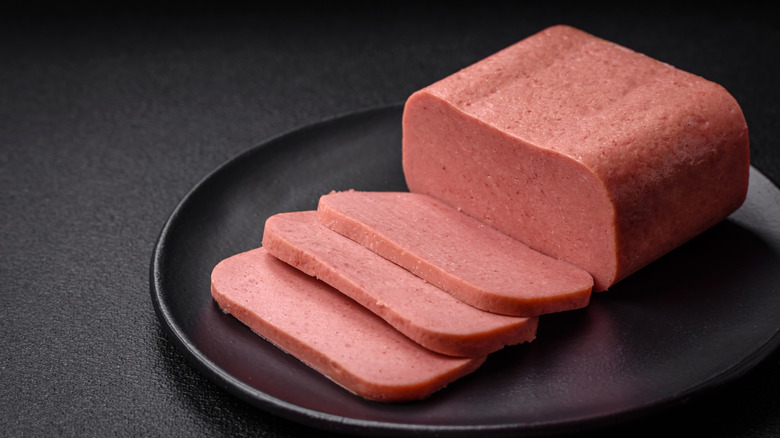 Sliced canned ham on a black plate