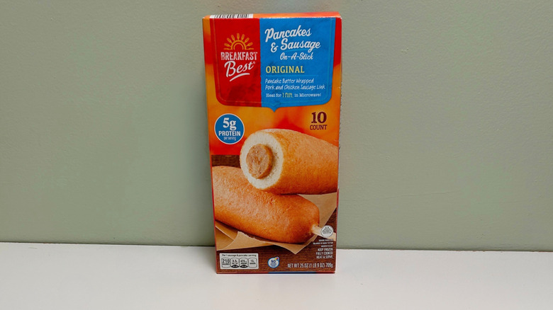 A box of Breakfast Best Pancakes and Sausage on a stick on a green and white background