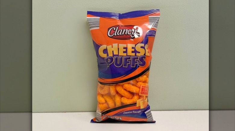 A bag of Clancy Cheese Puffs on a green and white background
